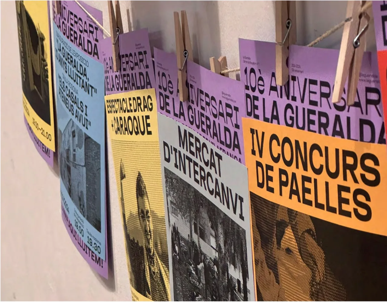 Overlapping coloured posters, such as the IV Concurs de Paelles and the Mercat d'Intercanvi, hung with pegs