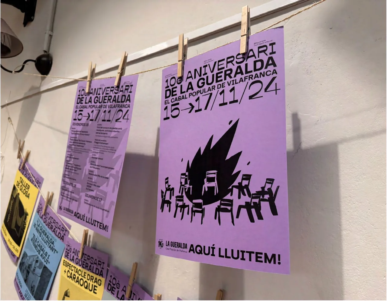Anniversary posters with the programme and an illustration of a bonfire with chairs, hanging on the line