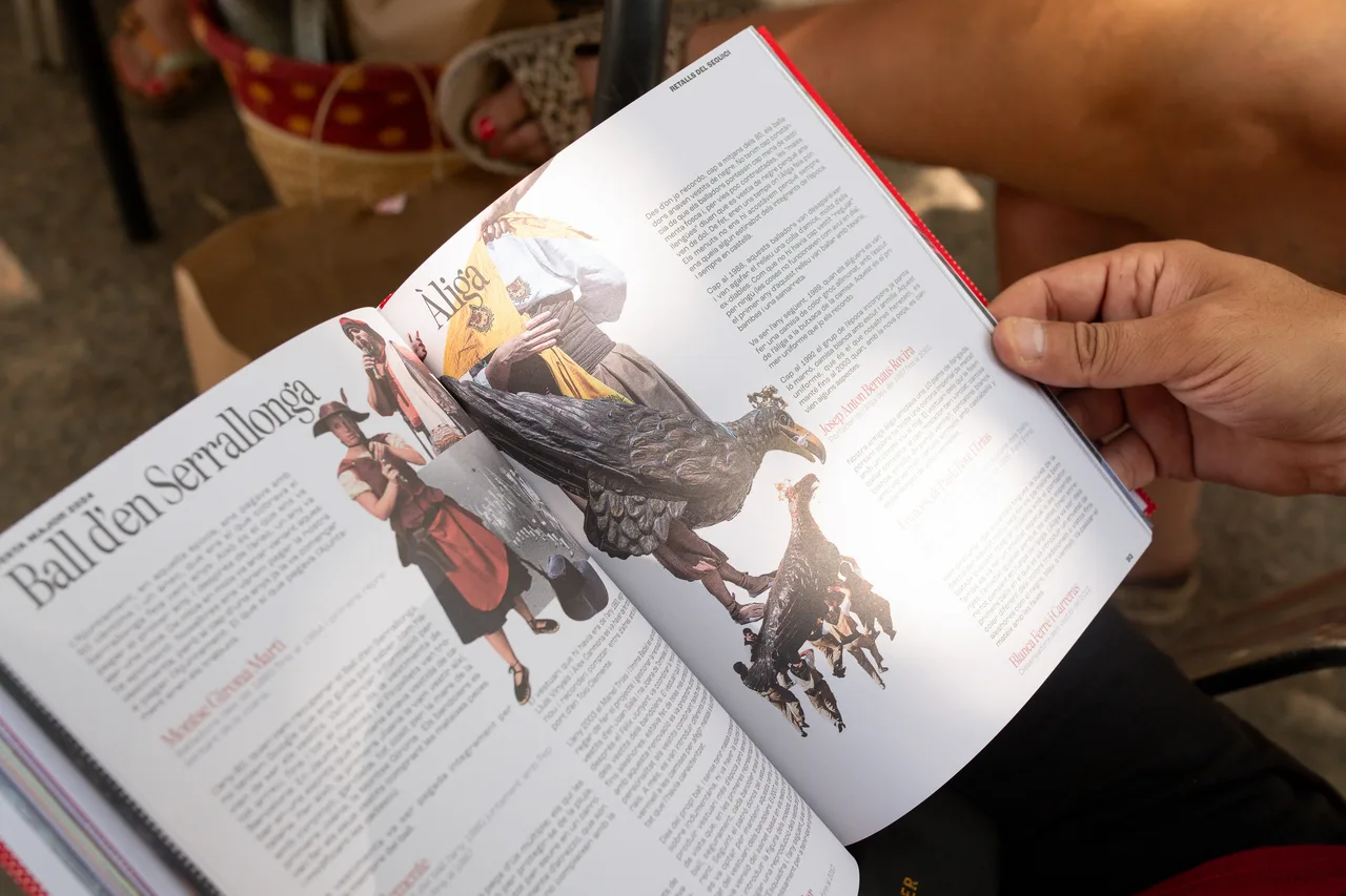 Town festival visual identity in the Festa Major book: hands opening an illustrated double page