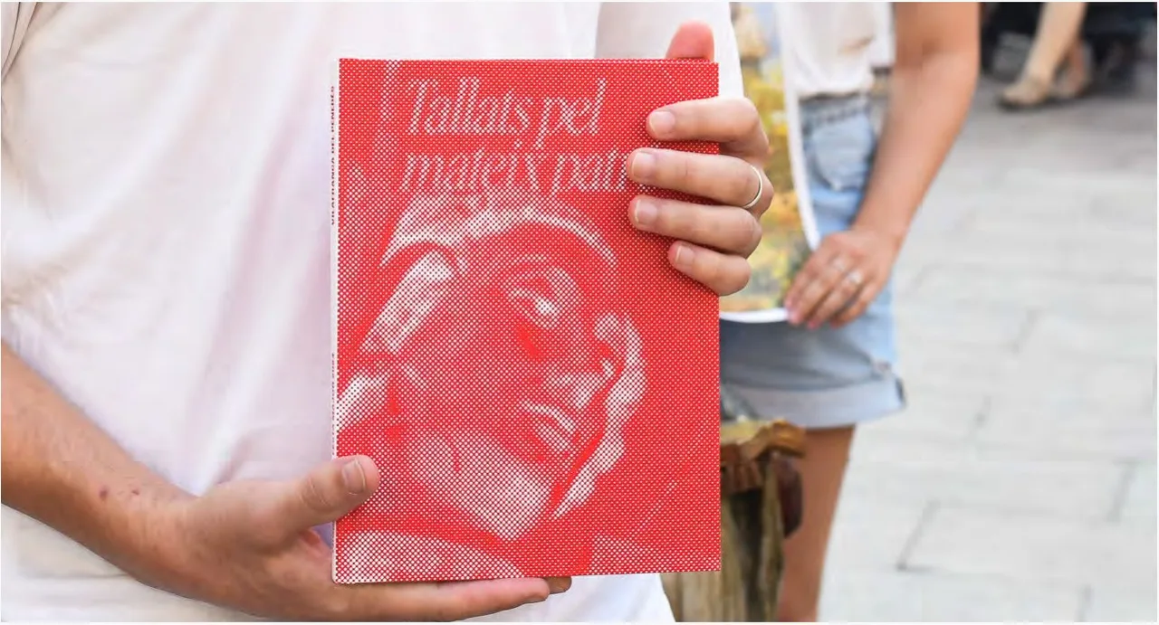 Persona sostenint el llibre de la Festa Major amb la coberta vermella
