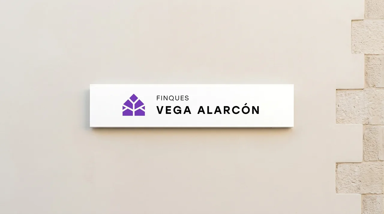 Placa de façana amb el logotip horitzontal de Finques Vega Alarcón sobre una paret clara amb carreus de pedra