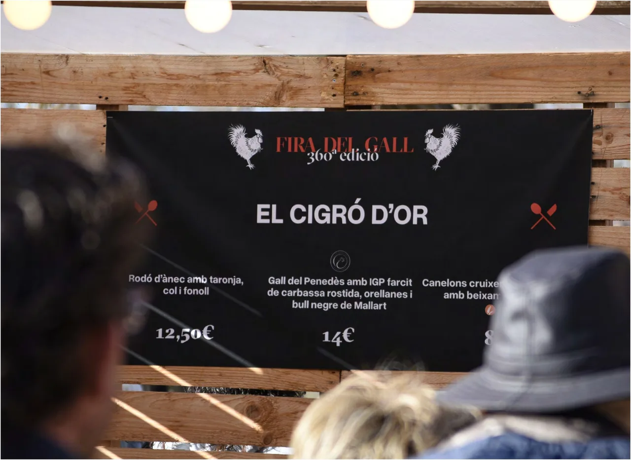 Black menu board for El Cigró d'Or with the fair logo and two roosters