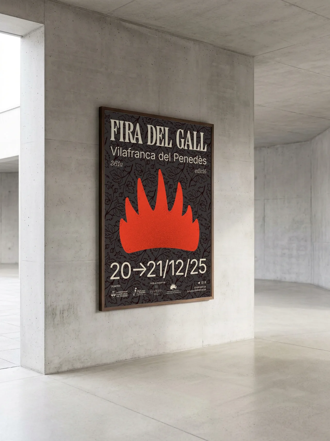 Fira del Gall 2025 poster in a dark wood frame in a concrete hallway, with a red flame on a vine-leaf background and the dates 20-21/12/25