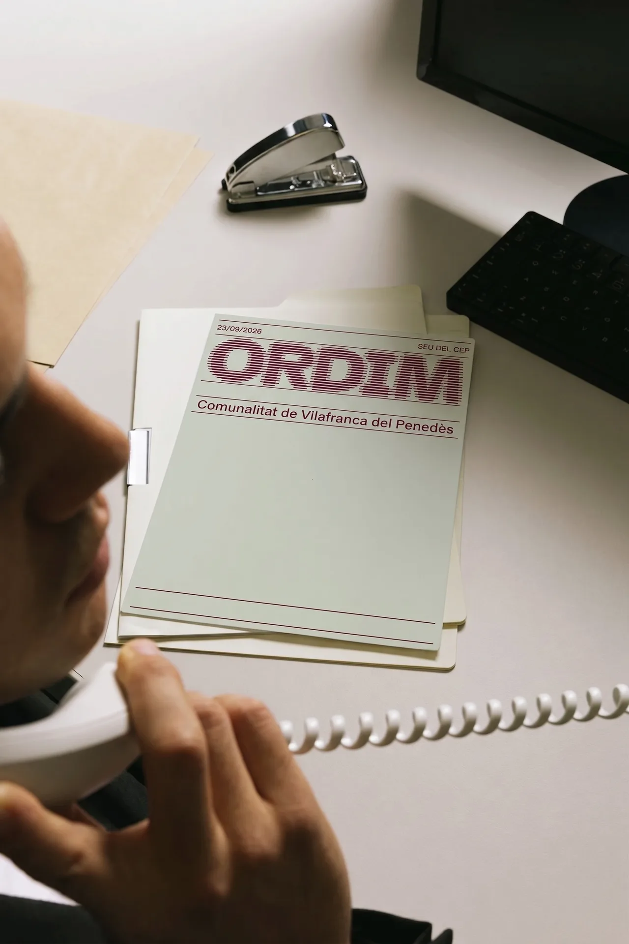 Paper de carta A4 d'Ordim sobre una taula d'oficina, mentre algú parla per telèfon