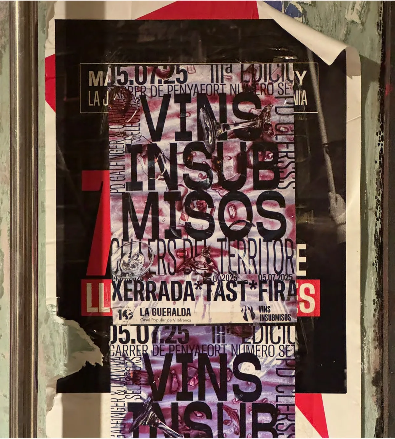 Vins Insubmisos 2025 poster pasted on a street board among other posters
