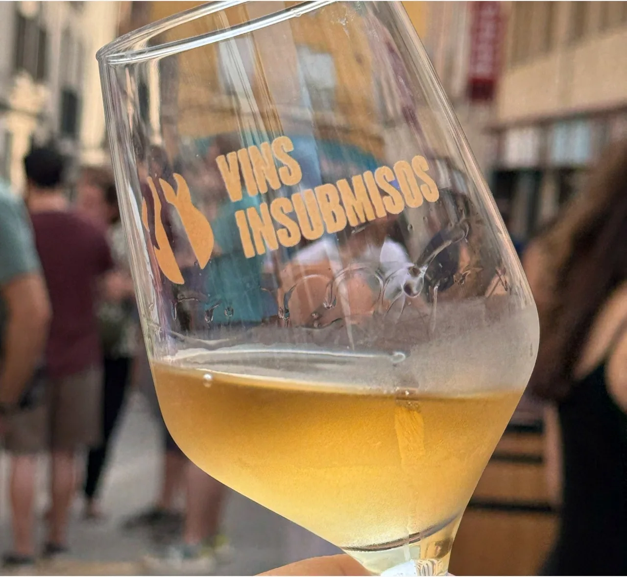 Wine glass with the Vins Insubmisos logo printed on it, in a Vilafranca street